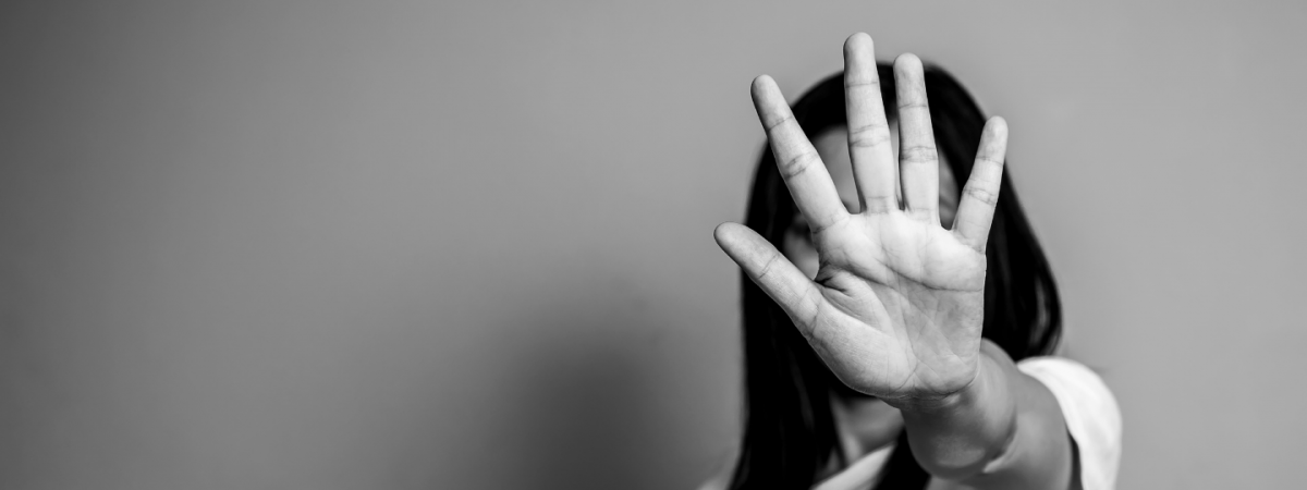 A woman holds up her hand in a defensive gesture, suggesting domestic violence.