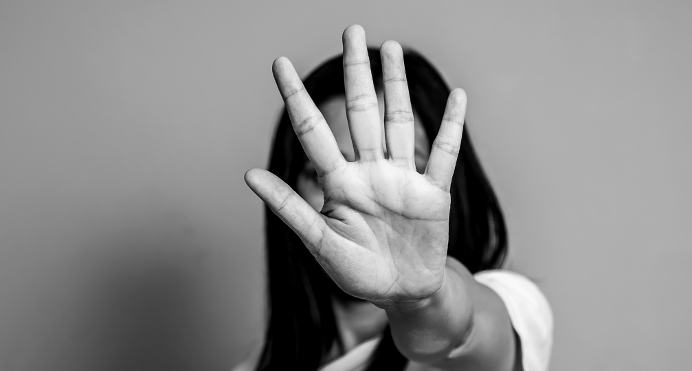A woman holds up her hand in a defensive gesture, suggesting domestic violence.