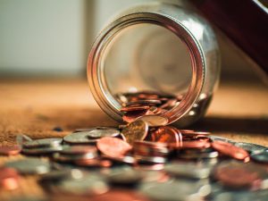 coins spilling out of a tipped over glass jar