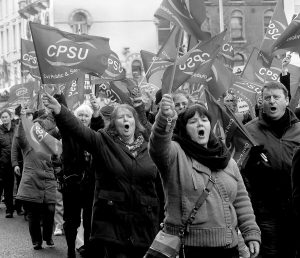 Women protesting outdoors waving lots of banners with the words CPSU.