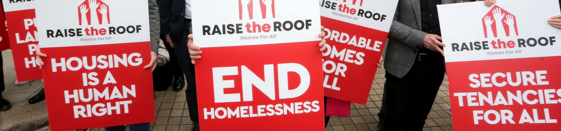 Posters saying end homelessness, raise the roof, for a rally on the housing crisis