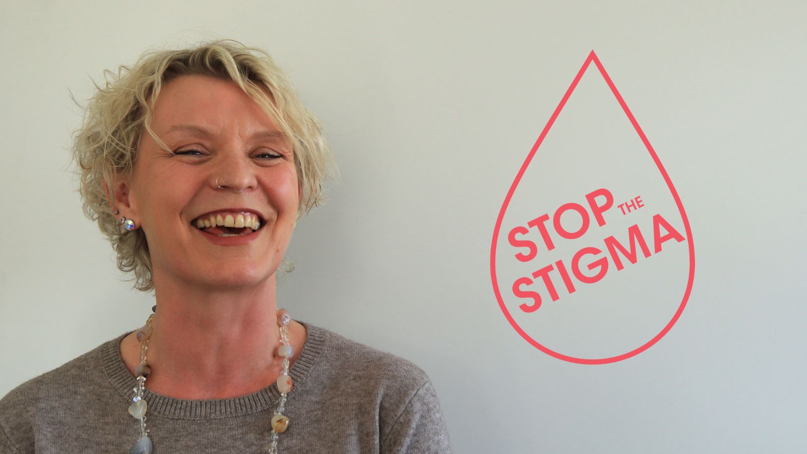 A woman smiling next to the stop the stigma logo. Representing what is period leave, menstrual leave?.