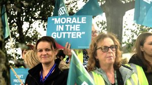 two forsa members at a protest holding a sign saying morale in the gutter