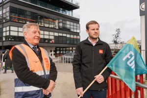 Driver testers stand outside Dun Laoghaire driver test centre holding Fórsa flags.
